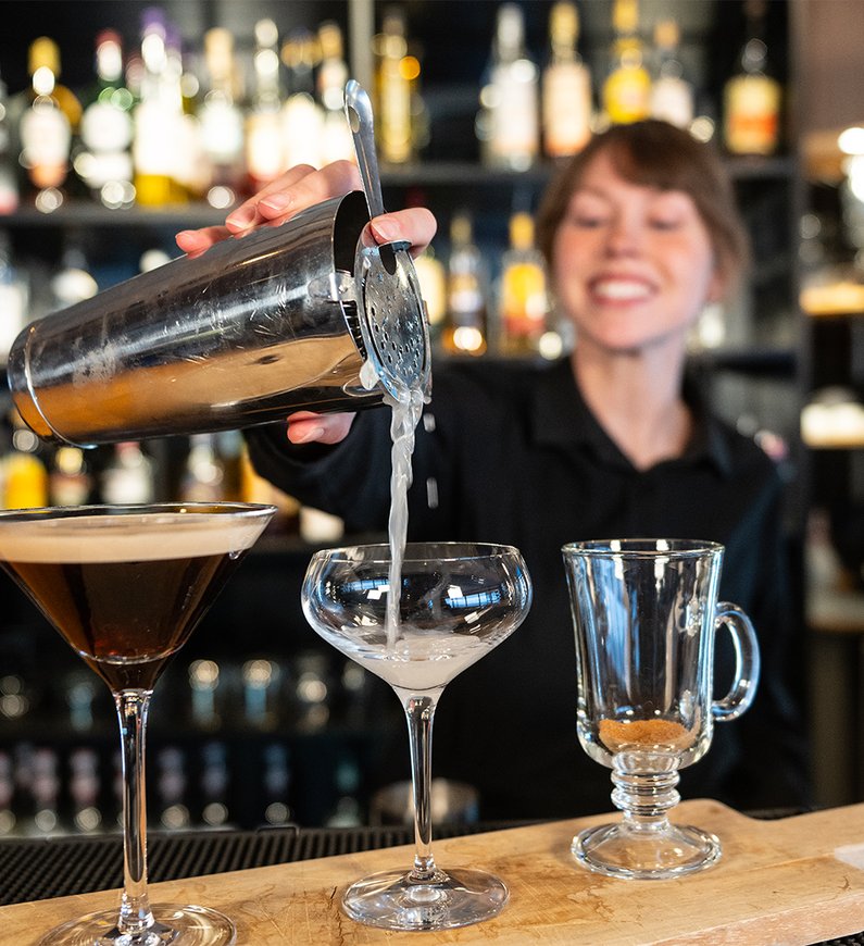 leende bartender häller upp skakade cocktails