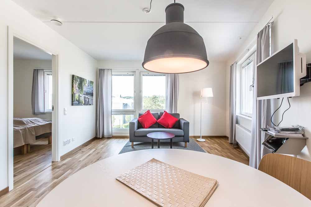 Apartment with round table, chairs, couch and large windows.