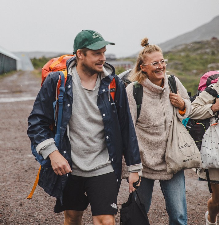 två glada människor går med packning en mulen dag