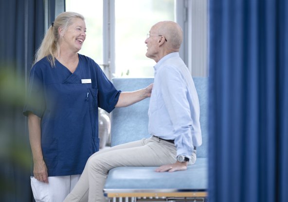 Kvinnlig läkare talar med manlig patient