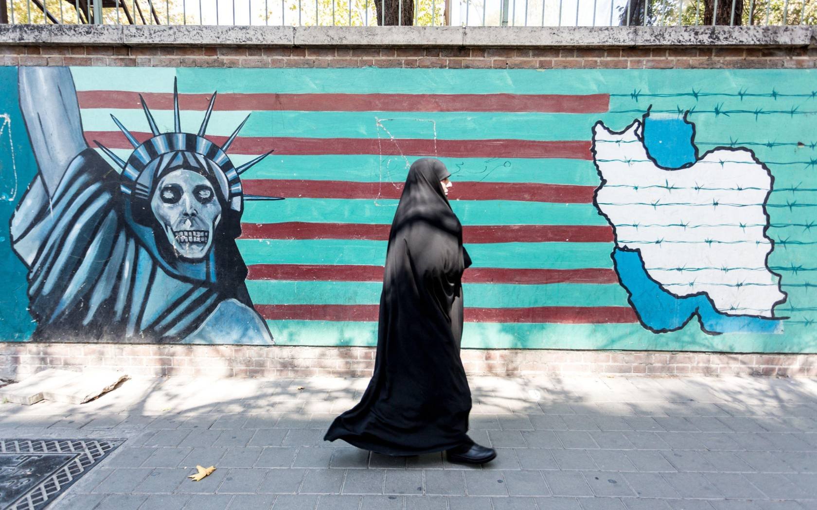 A woman walks in front of anti-American propaganda in Tehran.