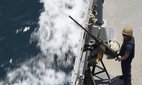 A US Navy sailor stands by a machine gun aboard the USS Paul Hamilton in the Strait of Hormuz, 19 May 2023.