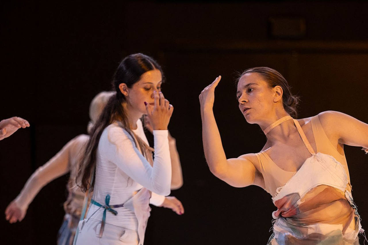 Dansarna på scen tittar på sina händer i rörelse.