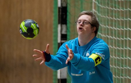 Handbollsmålvakt med kaptensbindel fångar bollen.