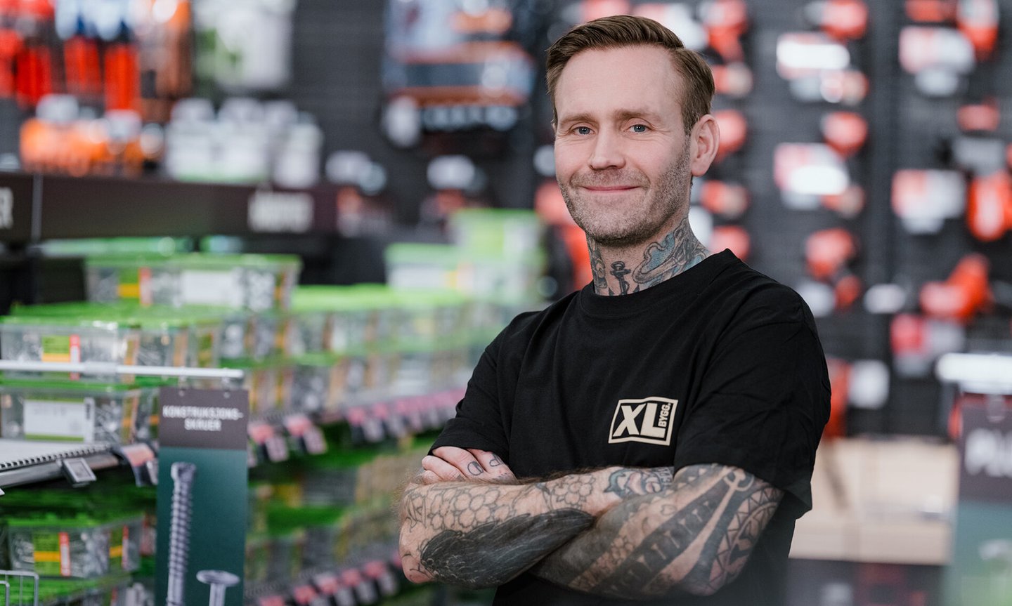tatovert ansatt i XL-BYGG smiler mot kamera
