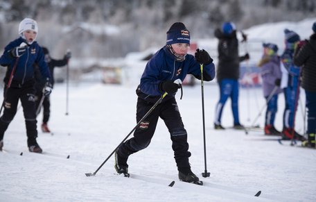 Ung längdskidåkare kämpar med blicken framåt.