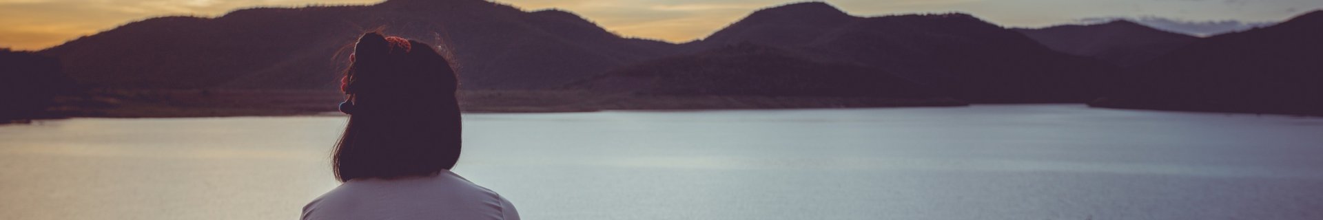 Ryggtavla på kvinna som tittar ut över sjö och berg