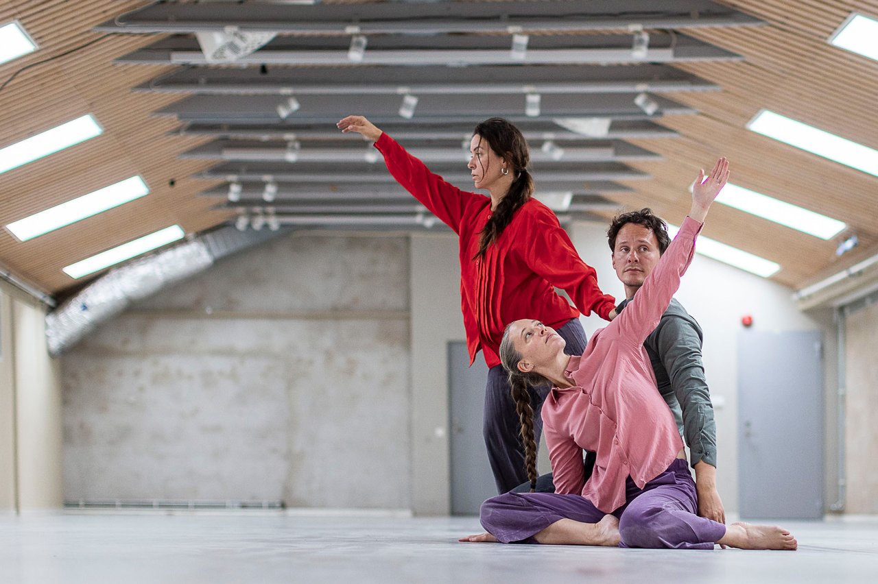 Tre dansare i ett kalt rum med takfönster.