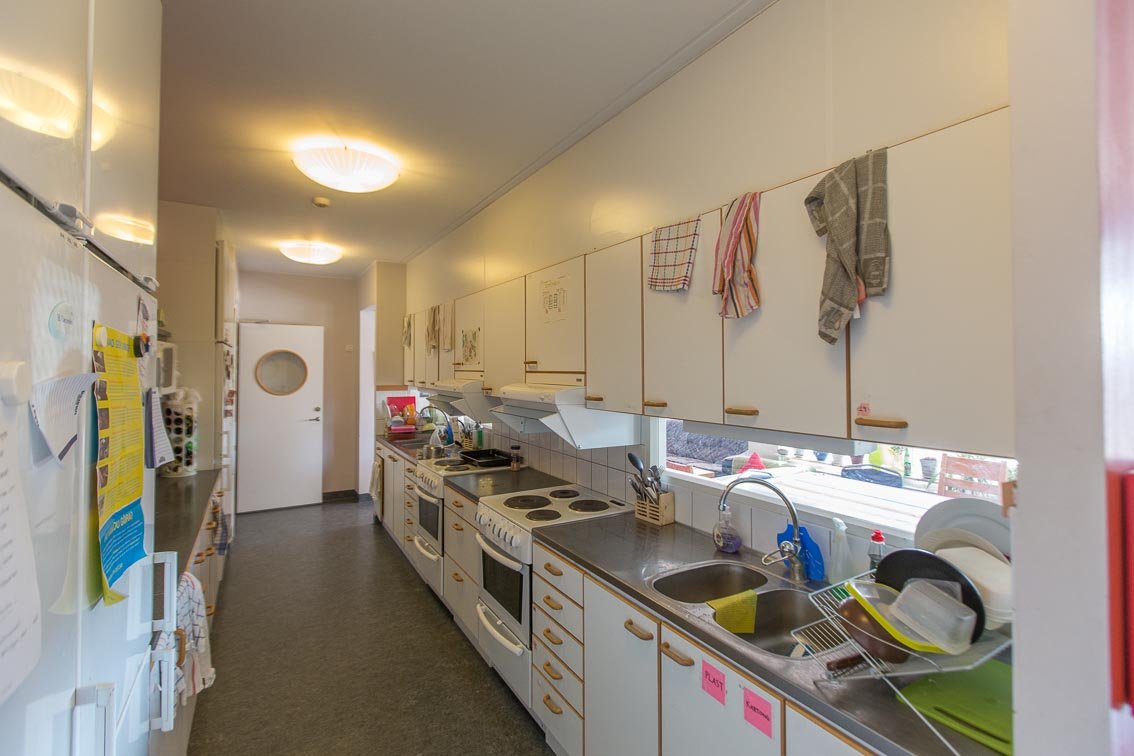 Common kitchen with two stoves, ovens and sinks. cupboards, refrigerator and freezer.