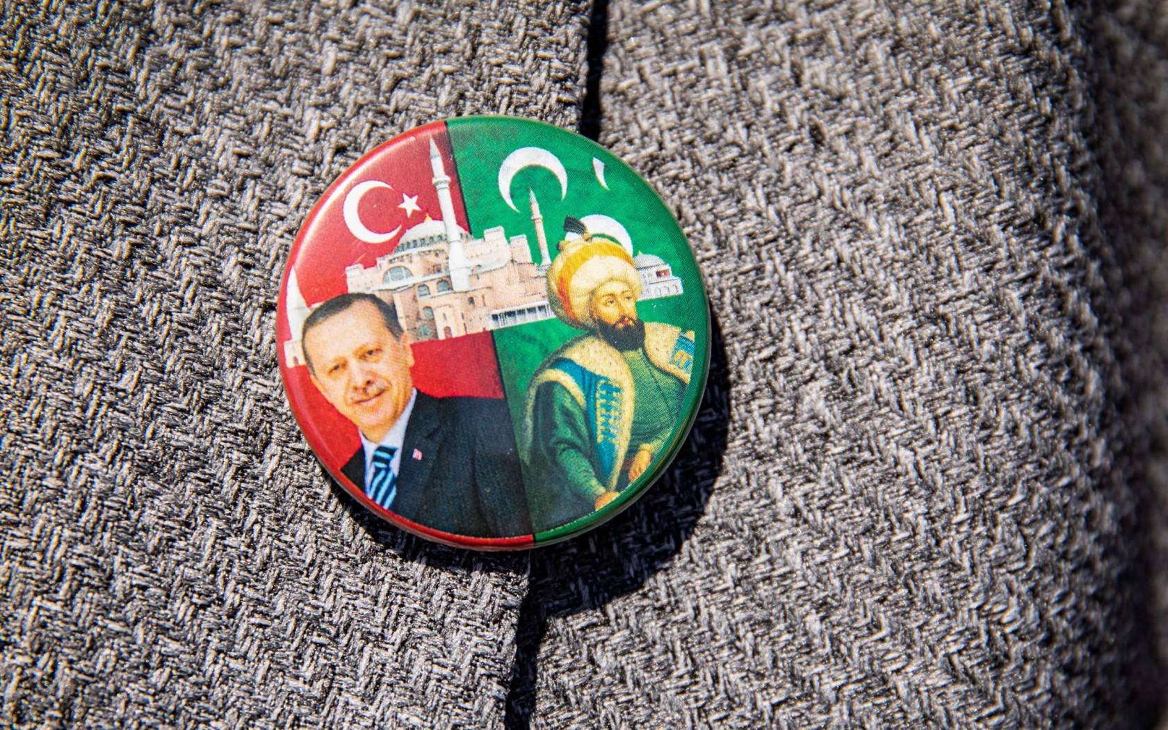 An attendee wears a badge depicting Recep Tayyip Erdogan, Turkey's president, left, during the opening ceremony to mark the first day of prayers at the Hagia Sophia mosque, in the Sultanahmet district of Istanbul, Turkey, on Friday, July 24, 2020. Turkey's President Recep Tayyip Erdogan is holding the first Islamic prayer at the iconic Hagia Sophia in nearly a century, a calculated move to boost the embattled Turkish presidents popularity at home and in the Muslim world.