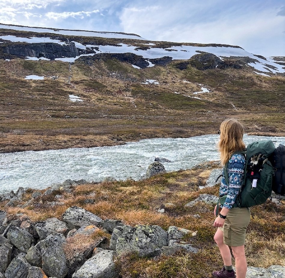 kvinna kollar ut mot en jokk och sn&ouml;t&auml;ckt fj&auml;ll en sommardag i shorts
