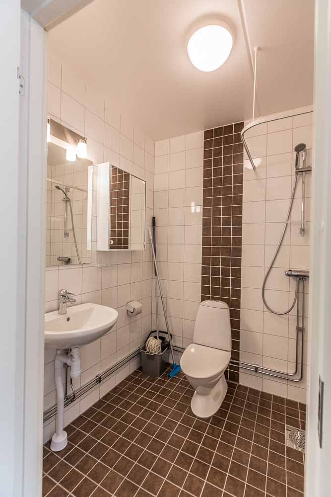 Tiled bathroom in white and brown. Sink, wc and shower.