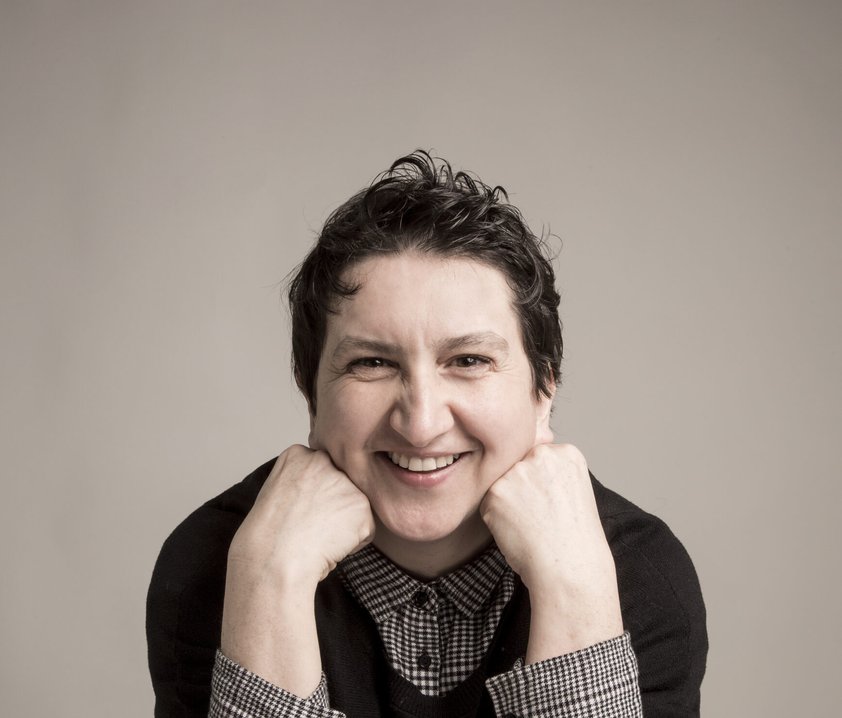 En leende person som vilar huvudet mot händerna.