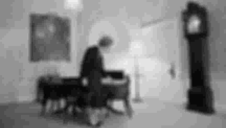 British Conservative prime minister Margaret Thatcher wipes crumbs off the table at 10, Downing Street, London, circa 1990. A painting of her predecessor Winston Churchill hangs on the wall behind her.
