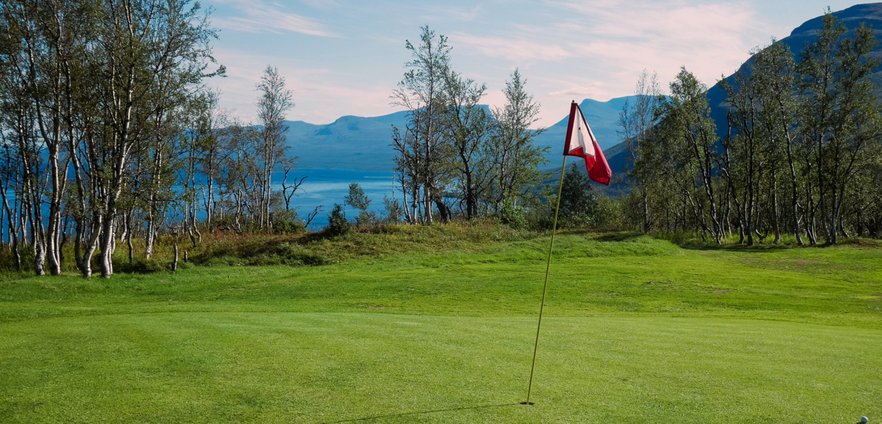 flagga p&aring; greenen p&aring; golfbanan med lapporten i bakgrunden