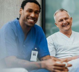 Happy mature male physician sitting with team in clinic