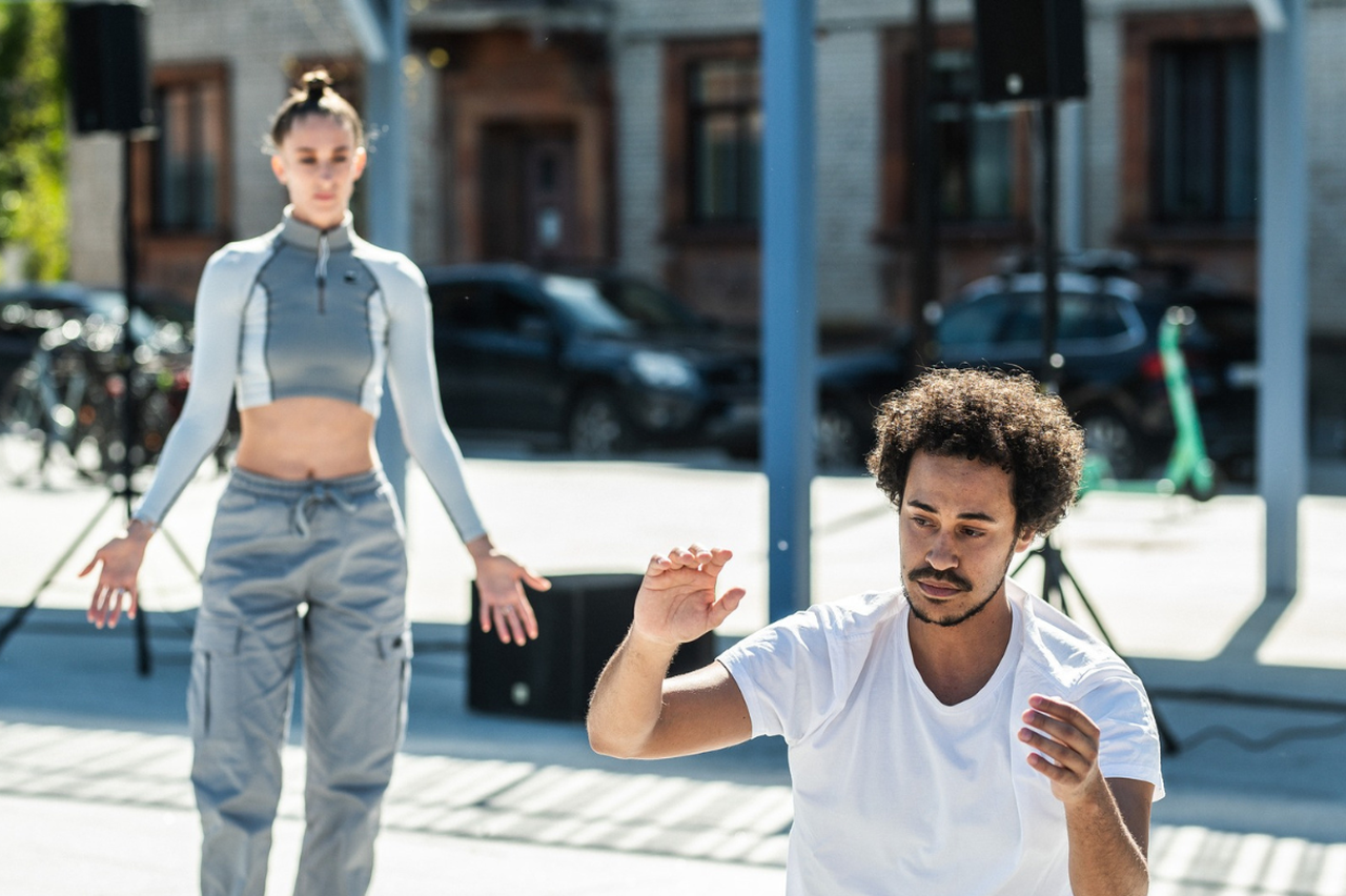 Dansarna dansar på en öppen plats i stadsmiljö.