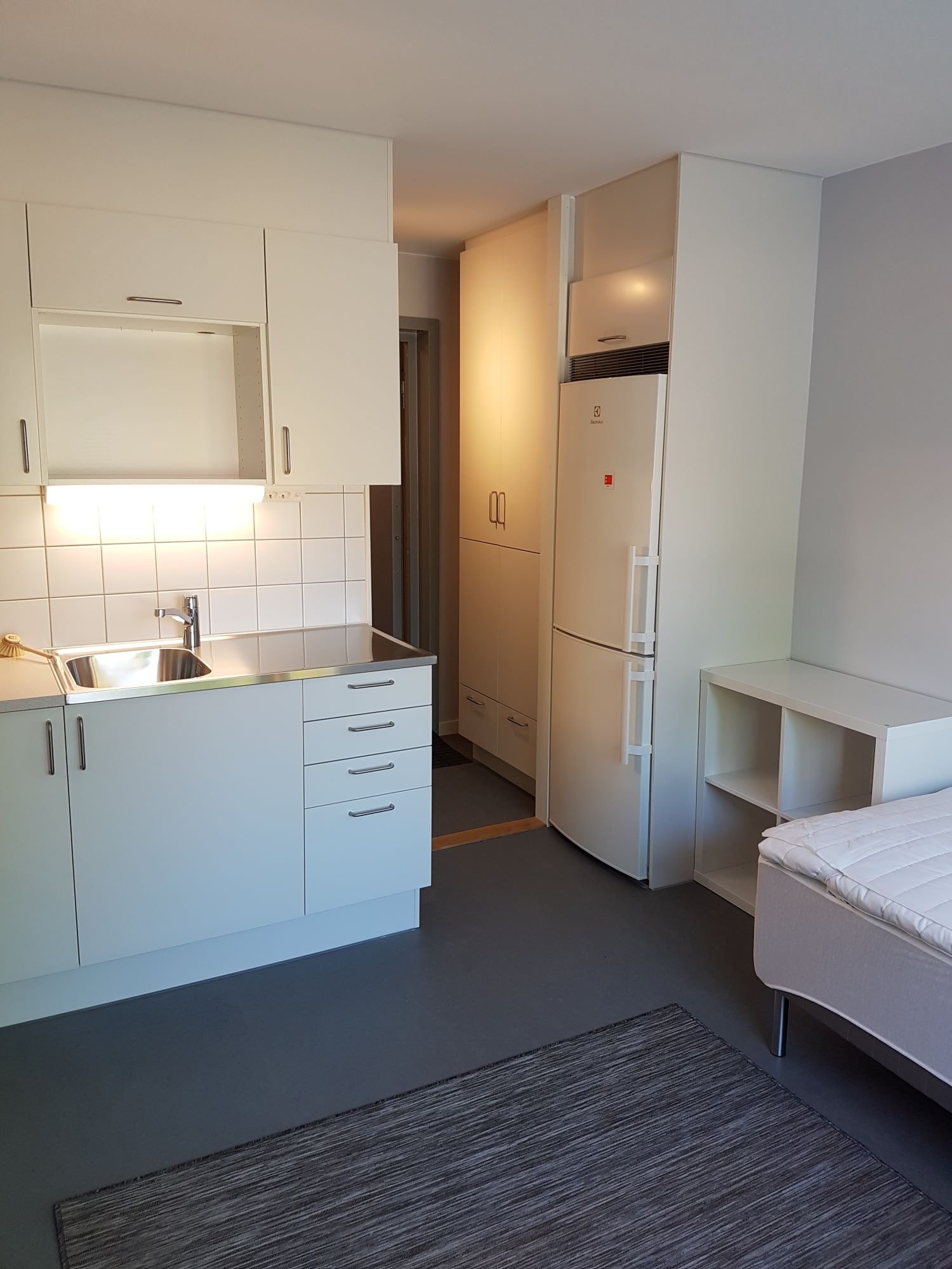 Studentroom with sink, refrigerator, freezer, storage unit and wardrobes.