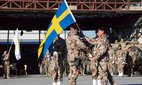 Swedish incoming commander Col. Micheal Claeasson, centre left, receives the Sweden flag from outgoing commander Col. Torbjorn Larsoon during a changing of command ceremony at the Provincial Construction Team compound in Mazar-i- Sharif, north of Kabul, Afghanistan, 2012.