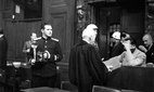 Soviet photographer Yevgeny Khaldei in the court room of the Nuremberg Trials while main defendant Hermann Goering covers his face with his hand. Credit: dpa picture alliance