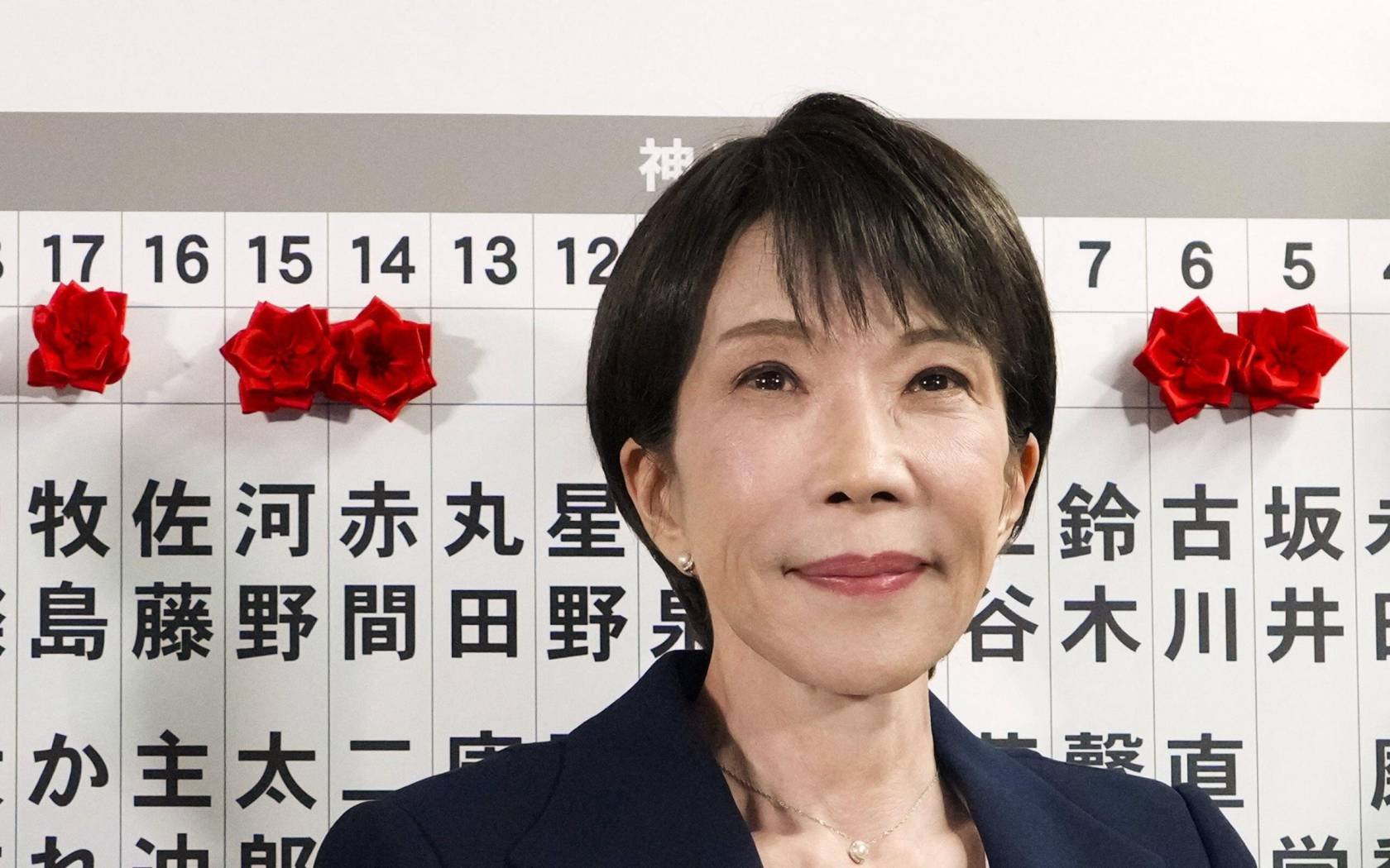 Japanese Prime Minister Sanae Takaichi poses for photos as she attaches a rosette to the name of a Liberal Democratic Party candidate.