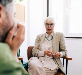 Female psychotherapist discussing with male patient sitting at therapy office