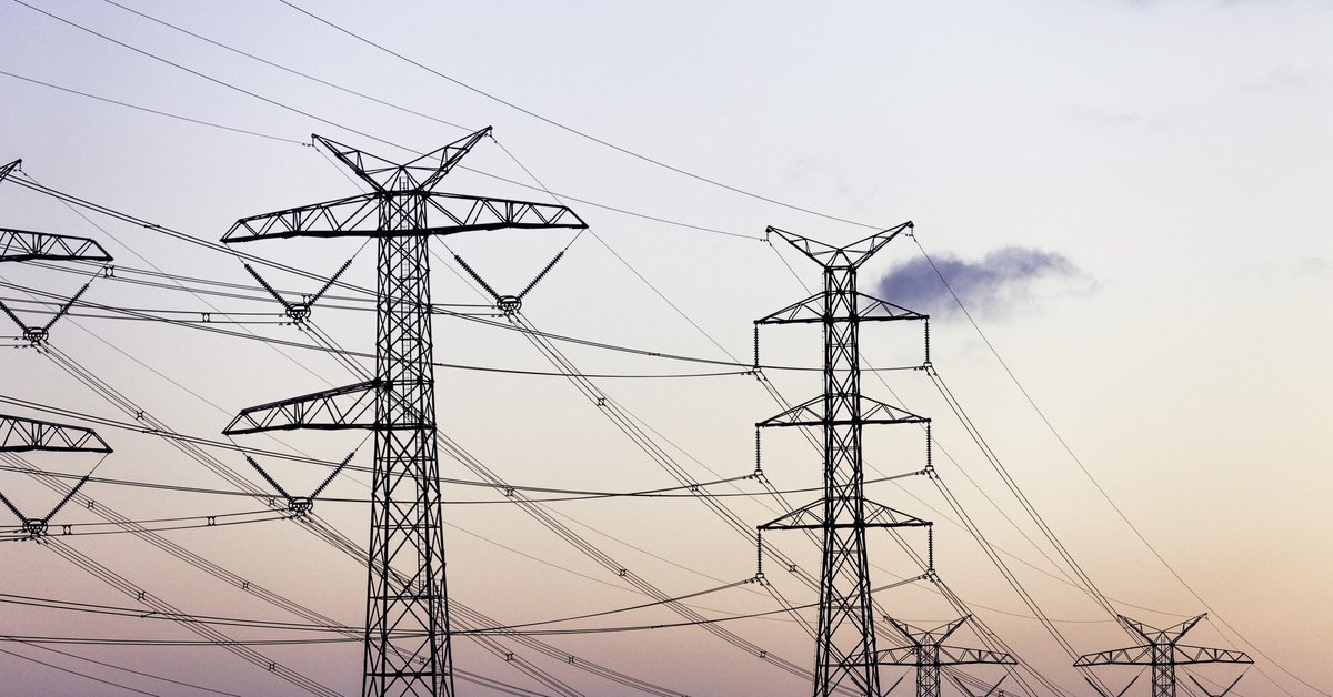 A row of dark power lines stands out against a vibrant sunset.
