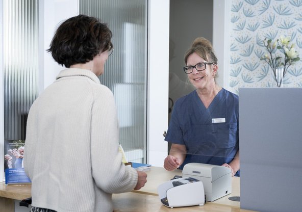 Patient pratar med sjuksköterska i reception