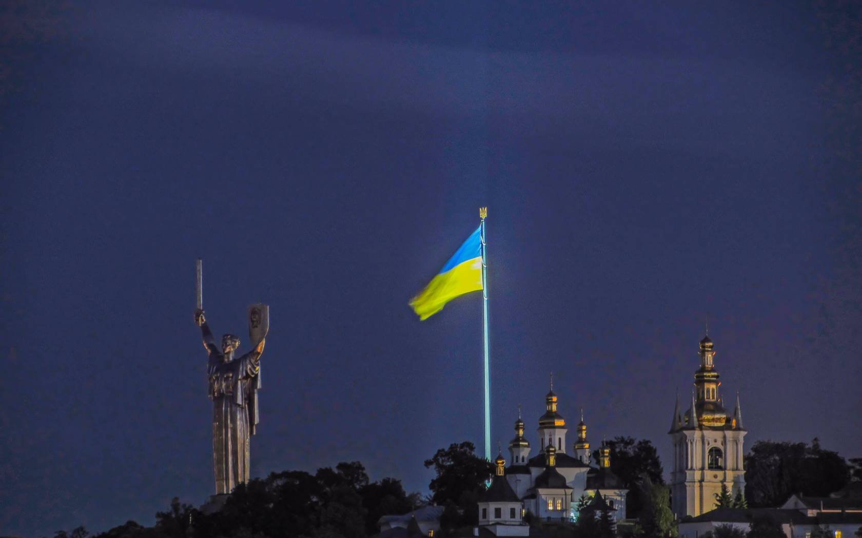 The national flag of Ukraine above the Kyiv skyline.