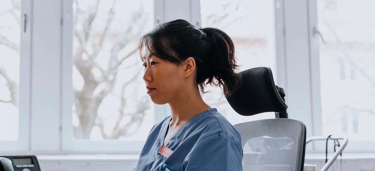 Female healthcare worker working on computer while sitting in examination room at hospital