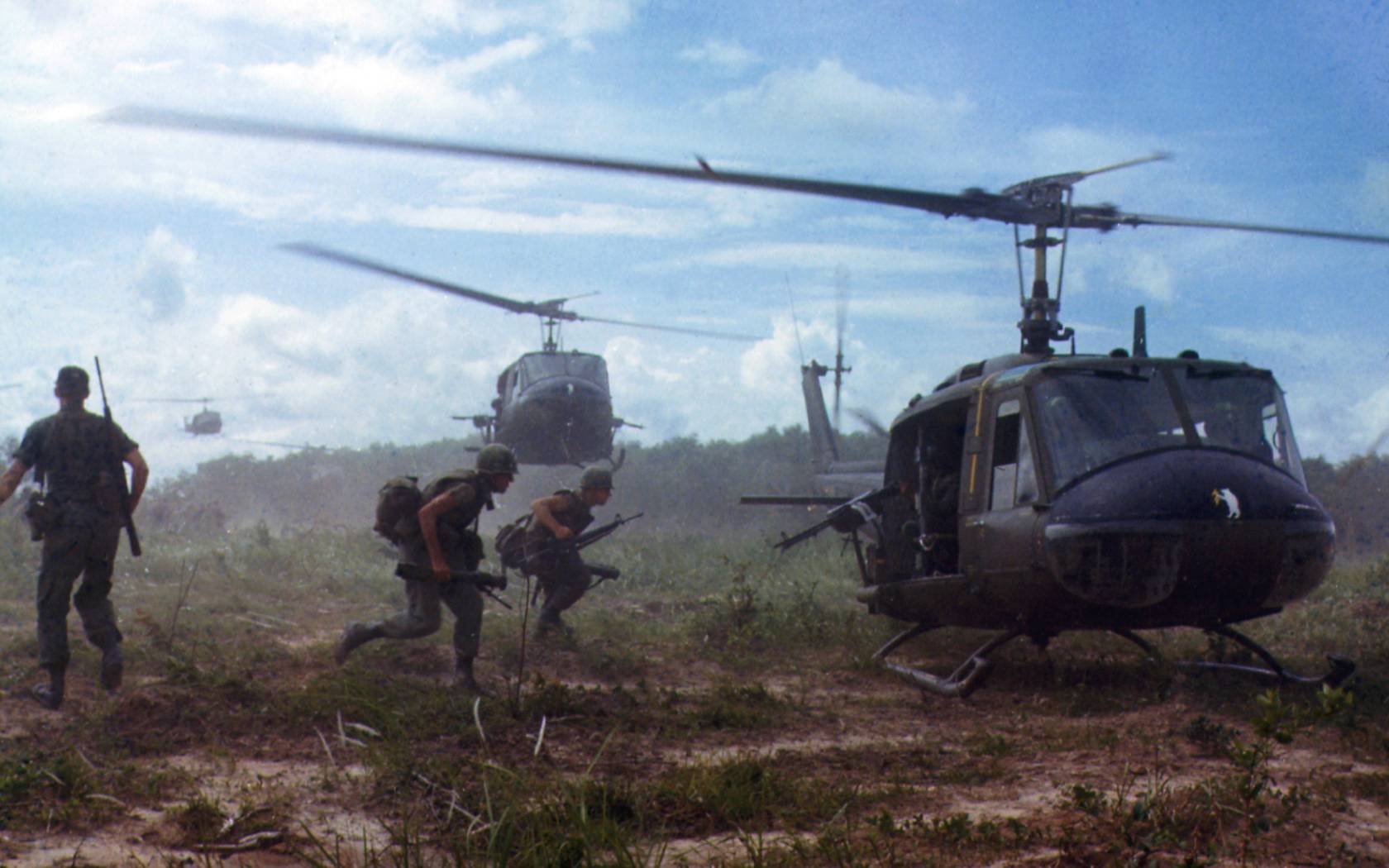 American troops running towards a helicopter during the Vietnam War.