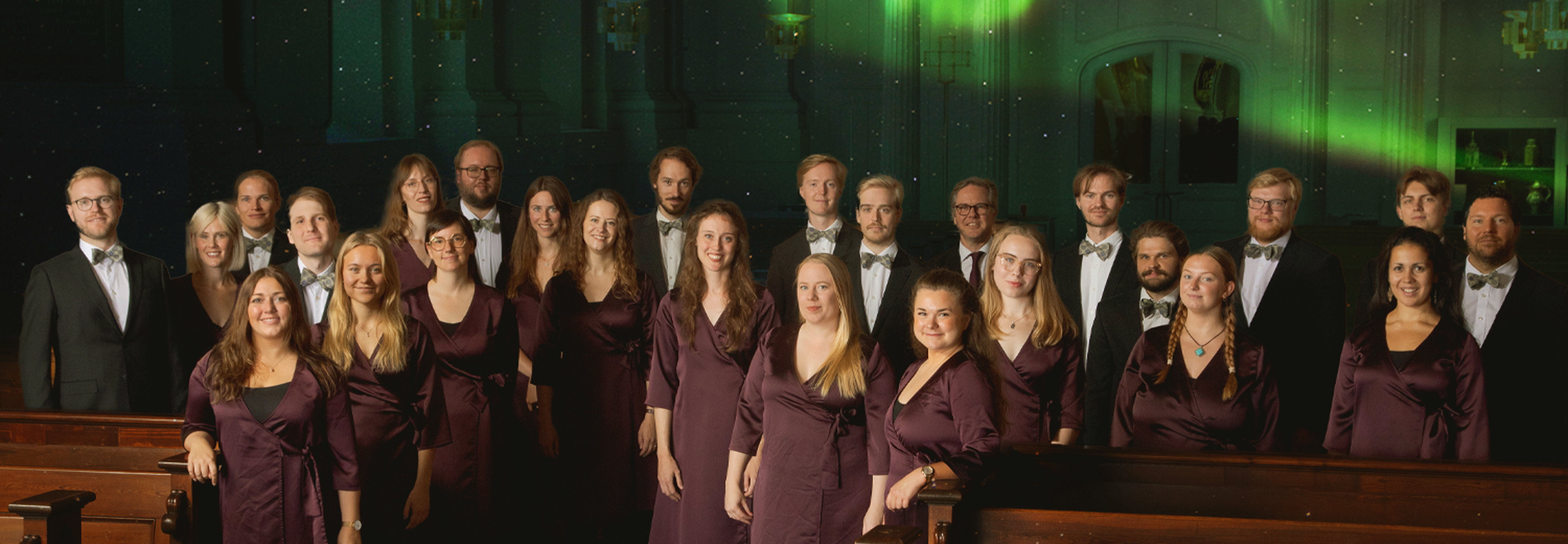 Körmedlemmar stående i kyrkgången med norrskenljus.