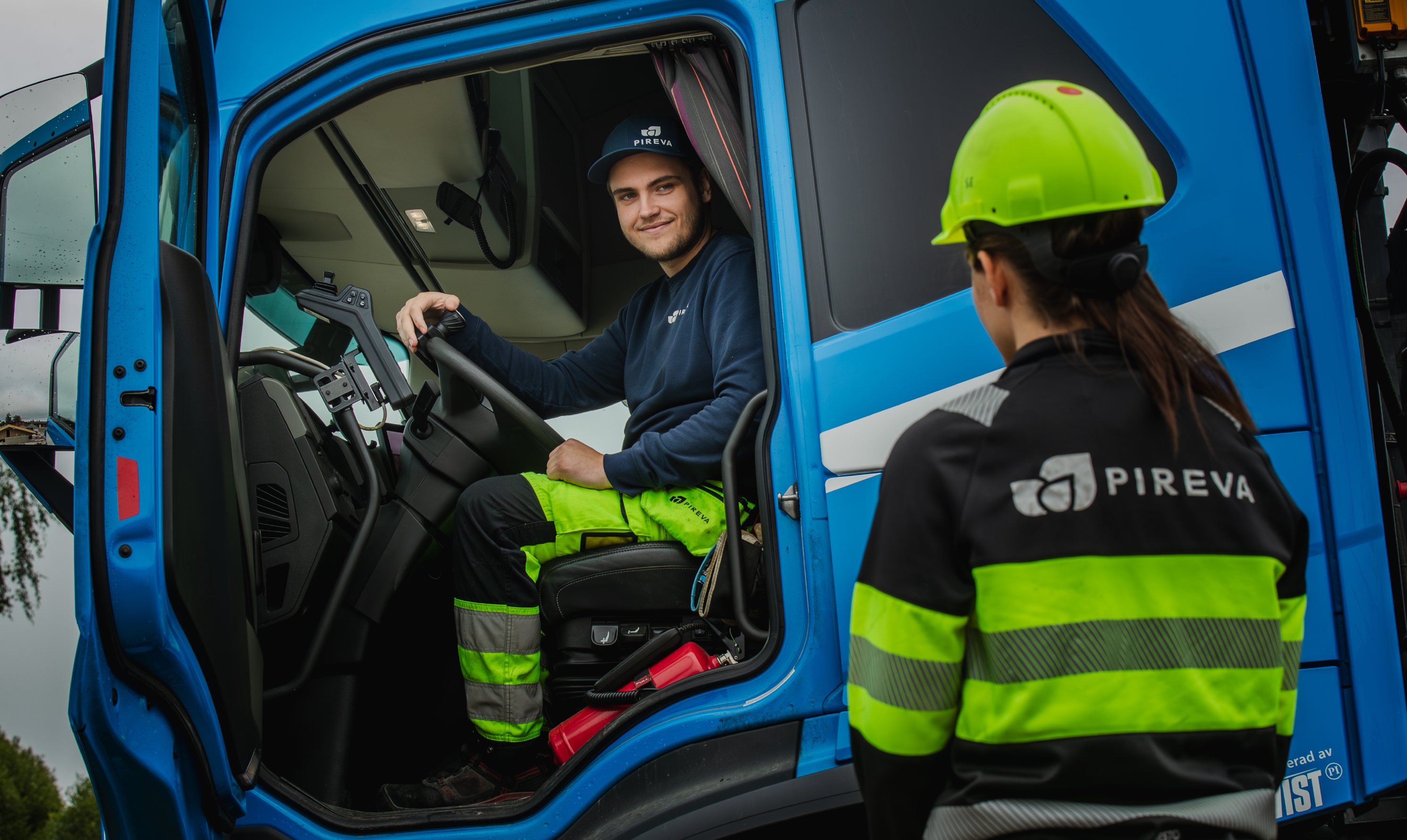 Chauff&ouml;r sitter i hytten p&aring; avfallsbil och samtalar med kollega