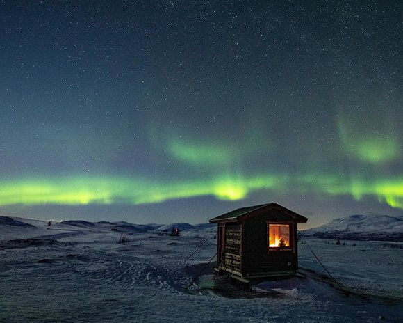 utsiktsstuga p&aring; fj&auml;llet under det dansande norrskenet