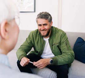 Leende man som pratar med en kvinnlig psykoterapeut på ett terapikontor