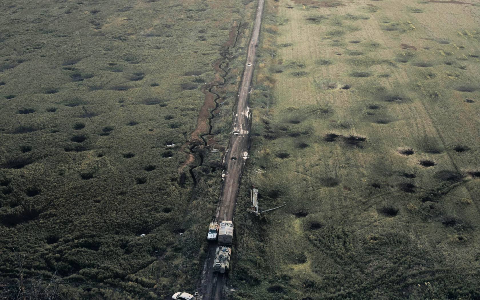A field and road covered with craters and wreckage near Kharkiv in Ukraine.