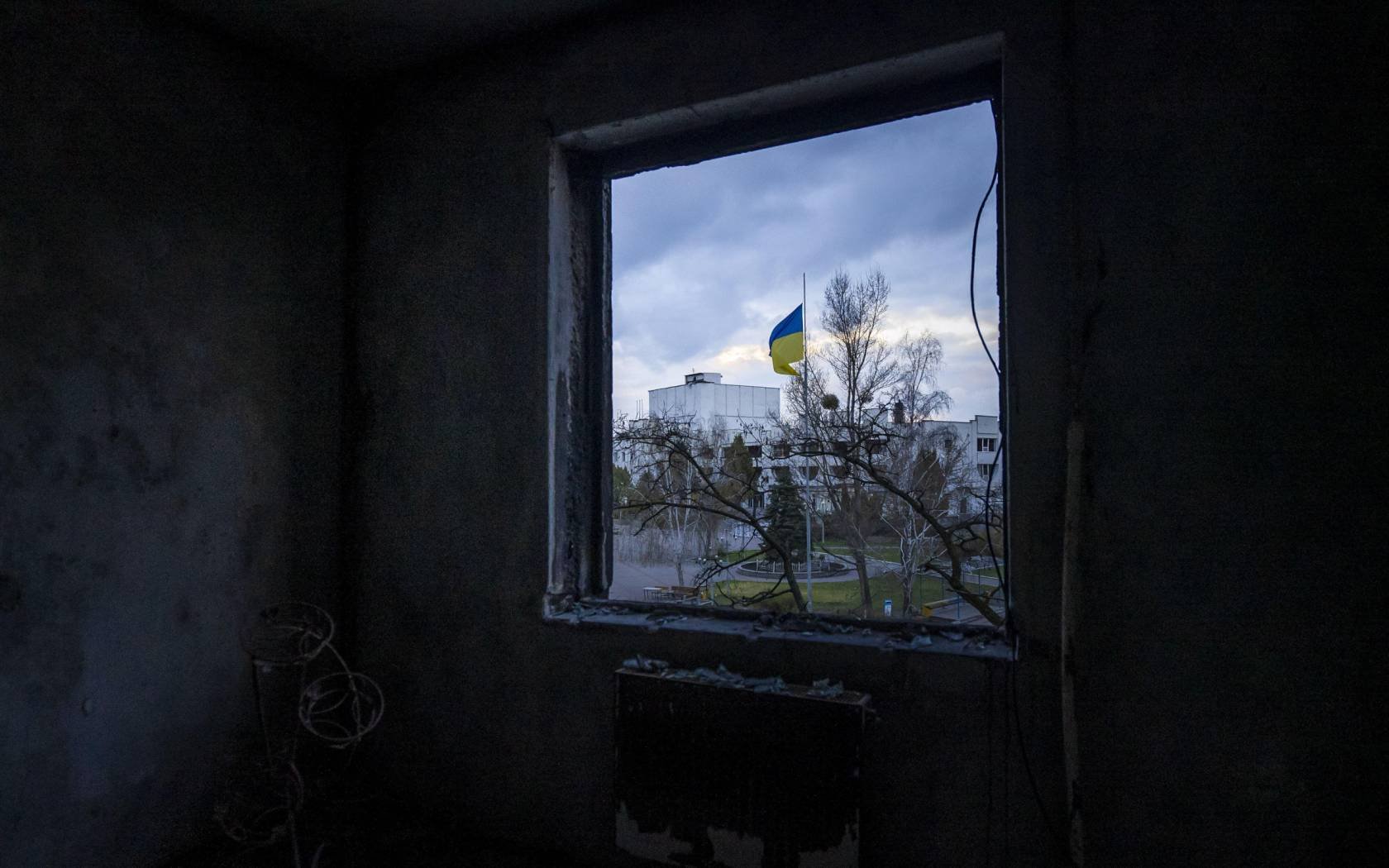 A Ukrainian flag is seen outside the window of a demolished room in an apartment building in Borodyanka, Ukraine, April 21, 2022. Credit: UPI / Alamy Stock Photo.