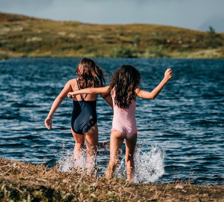 tv&aring; flickor springer in i en fj&auml;llsj&ouml; f&ouml;r att bada