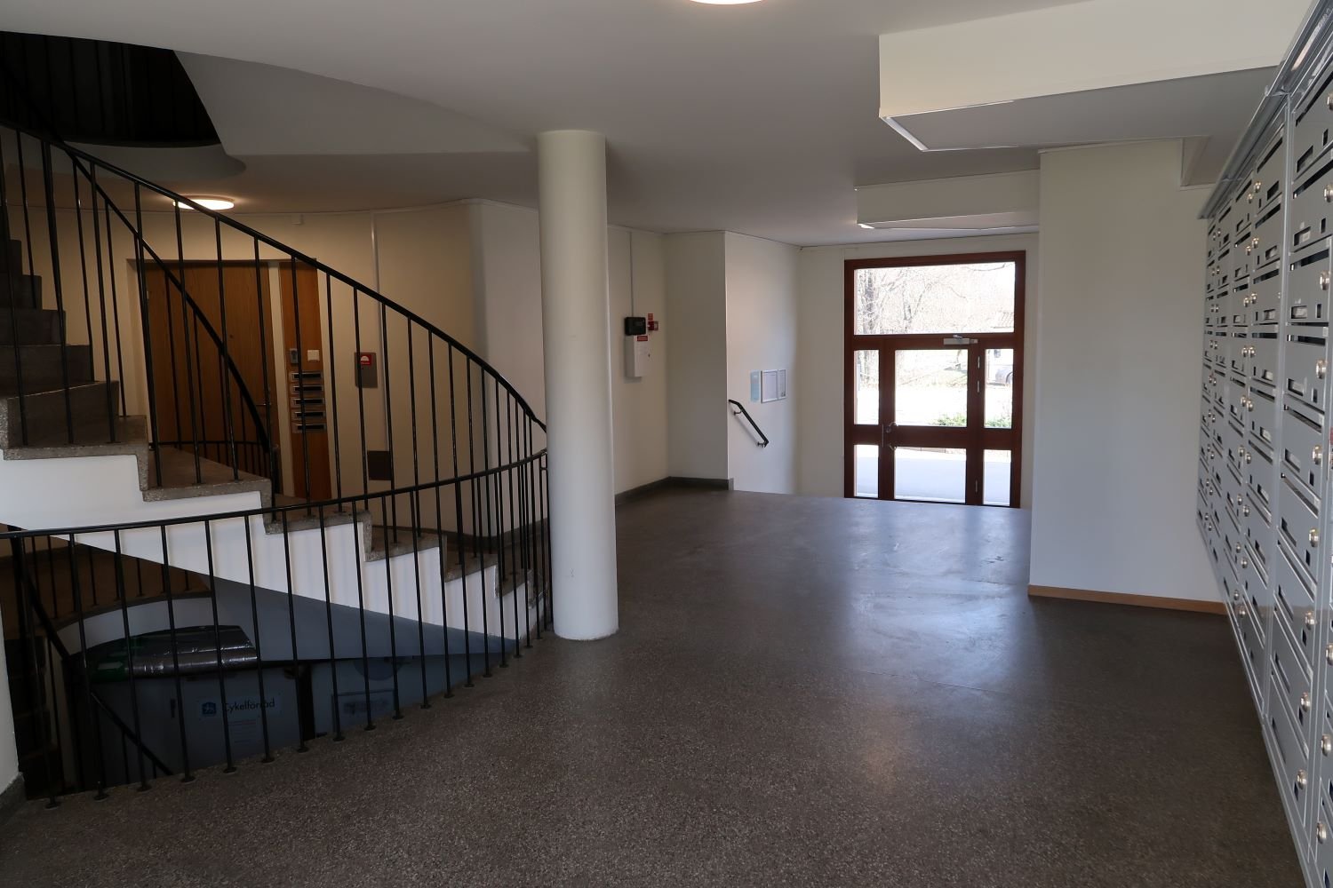 Inside the building entrance. A stairwell, large windowed doors and a wall with mailboxes.