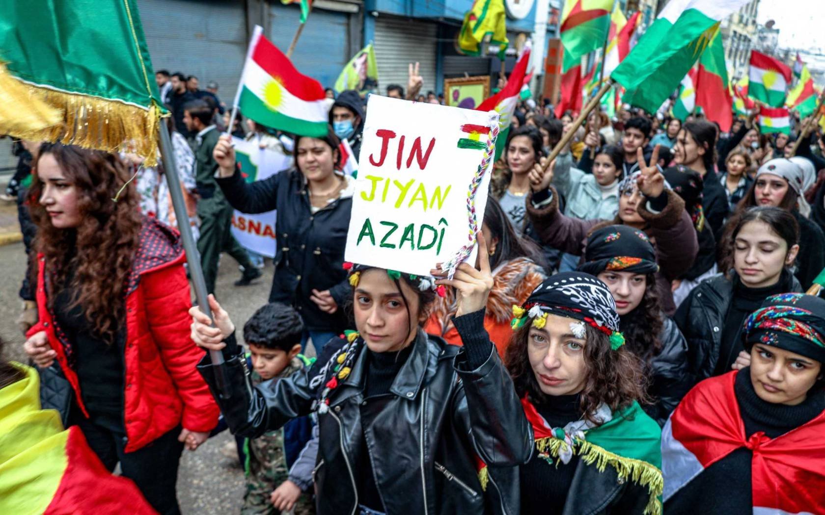 A demonstrator holds a placard bearing the slogan 'Women, Life, Freedom' during a demonstration in Qamishli, northeastern Syria on January 19, 2026.