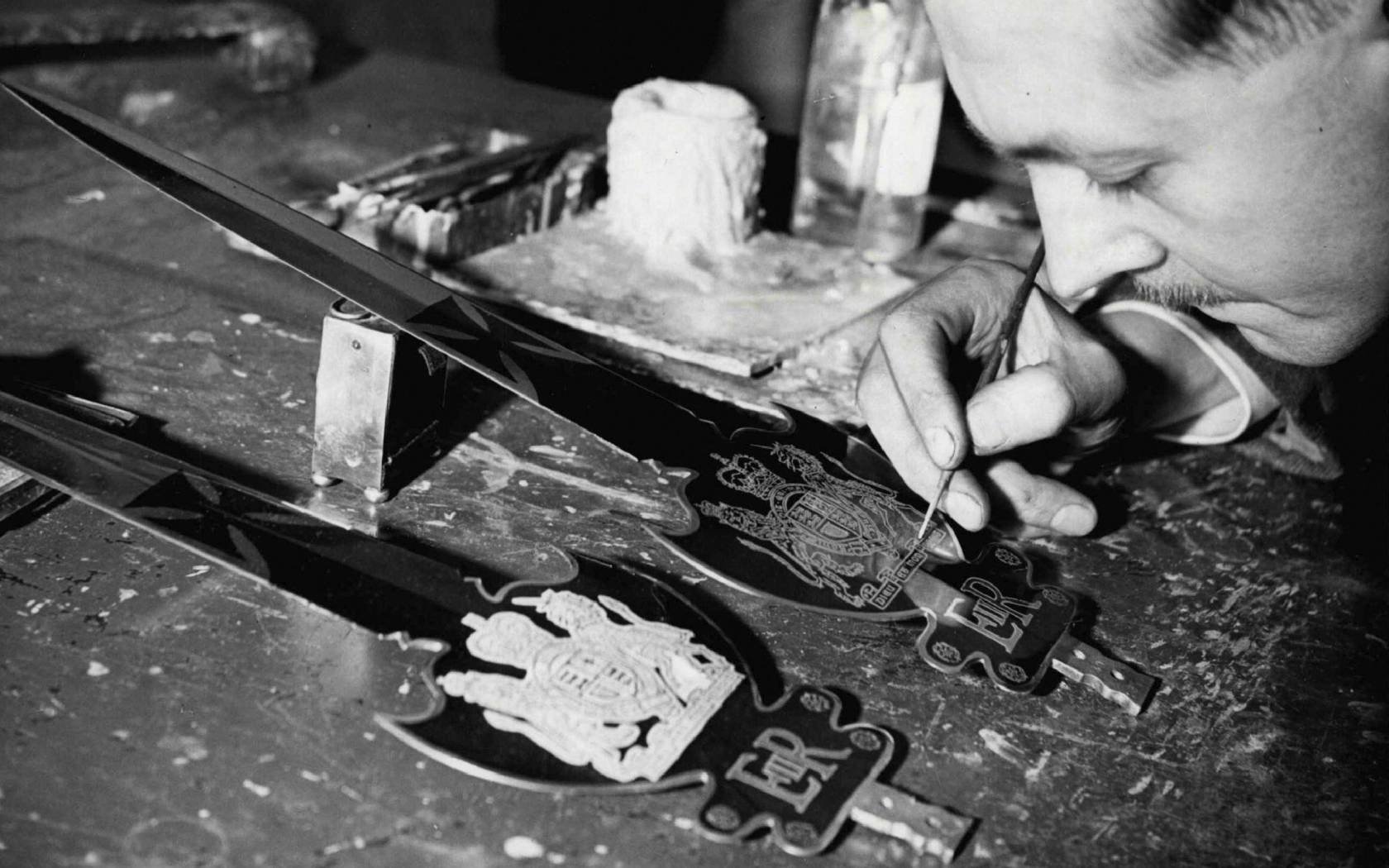 A craftsman is seen etching and embossing a ceremonial sword.
