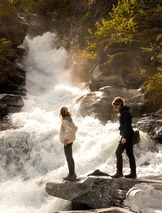 Two friends are looking at a waterfall in Björkliden