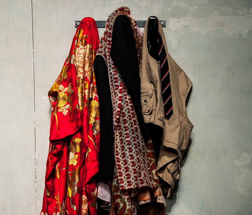 En vit vägg med tre krokar där det hänger kläder.