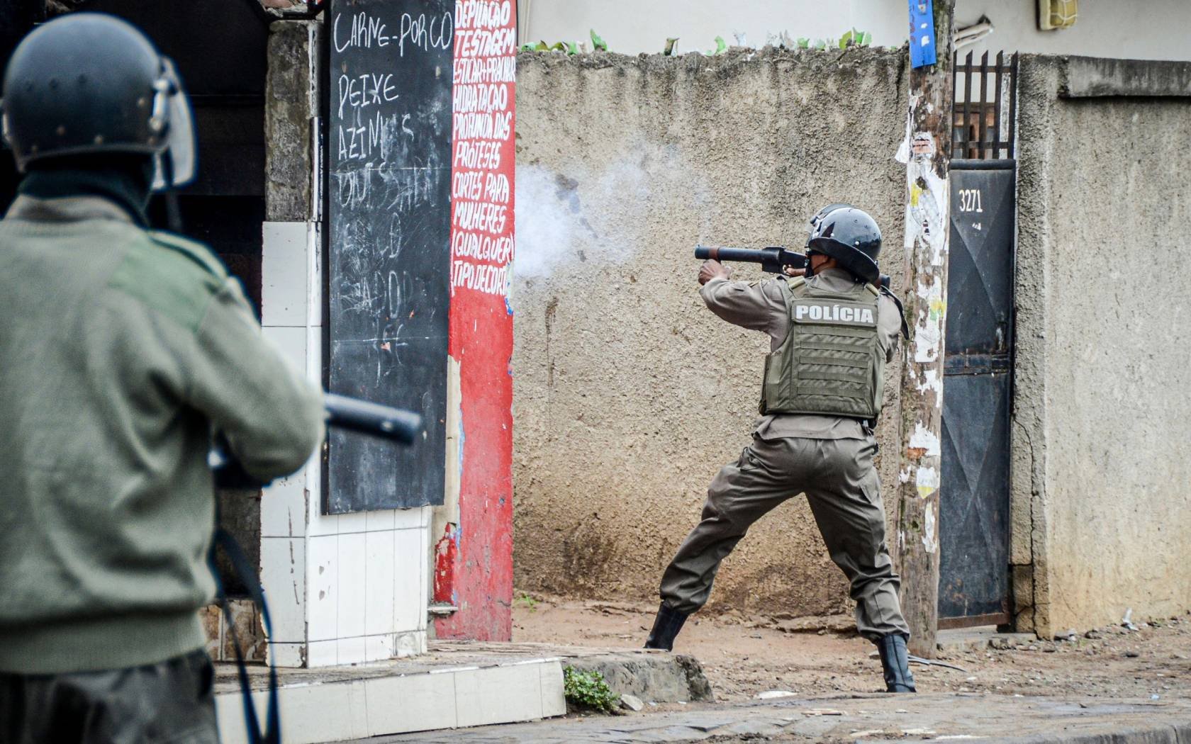 A police officer aims his weapon at protesters in Maputo, Mozambique.