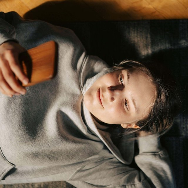 High angle view of young woman using smart phone while lying down with hand behind head