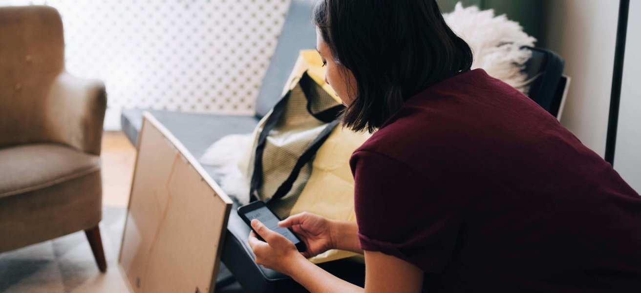 Woman using mobile phone while sitting in new home