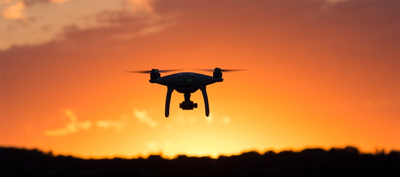 En drönare flyger i soluppgång.