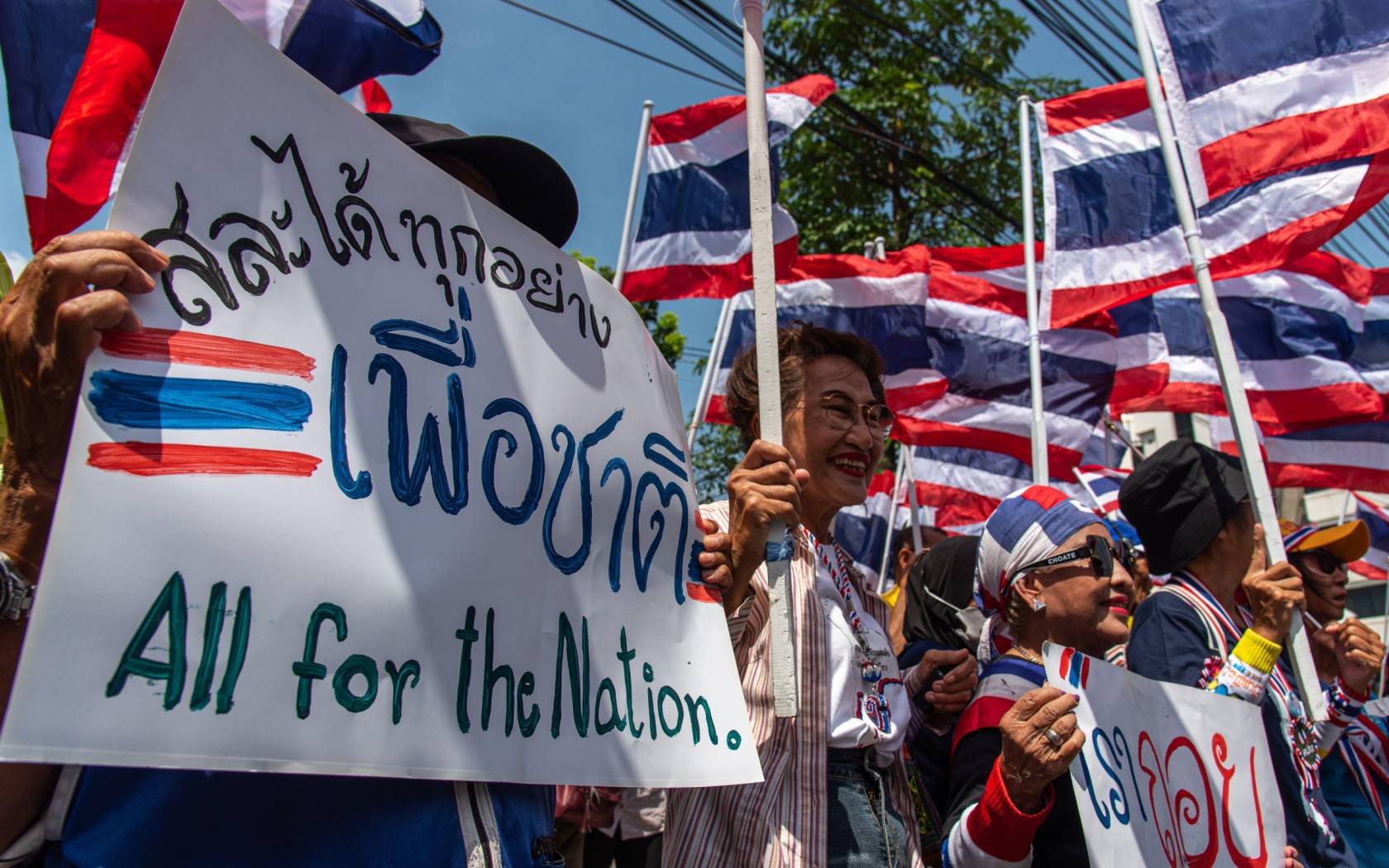 Protesters seen holding placards and the Thai national flag during a protest over the Thailand - Cambodia border conflict.