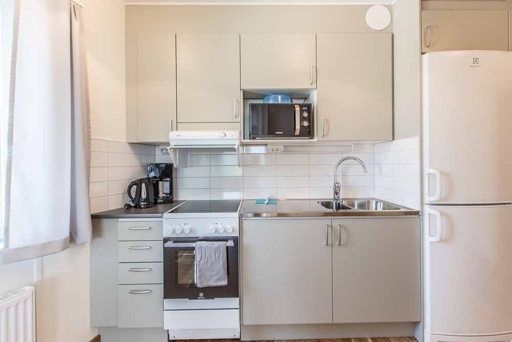Kitchen with stove, oven, sink, microwave, kettle, refrigerator, freezer and cupboards.