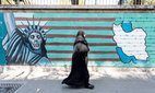 A woman walks in front of anti-American propaganda in Tehran.